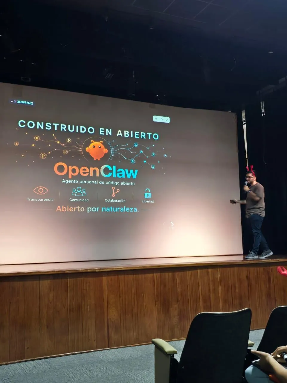 Sergio presenting the 'Construido en abierto' slide: OpenClaw as an open-source personal agent built on transparency, community, collaboration and freedom
