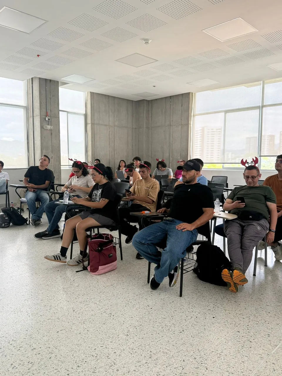 Attendees seated, several wearing lobster-claw headbands, with the city skyline visible through the windows